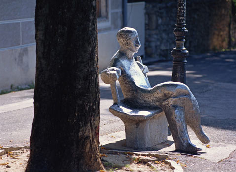 Скульптура человека сидящего на скамье